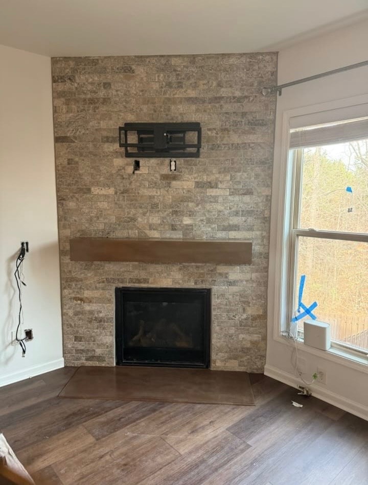 Fireplace renovation – stone tile surround with wood mantel and hardwood flooring