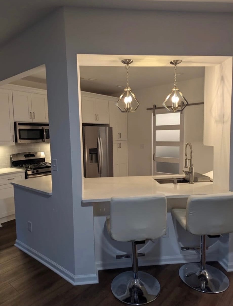 Kitchen renovation – white cabinetry with breakfast bar, pendant lighting and stainless appliances