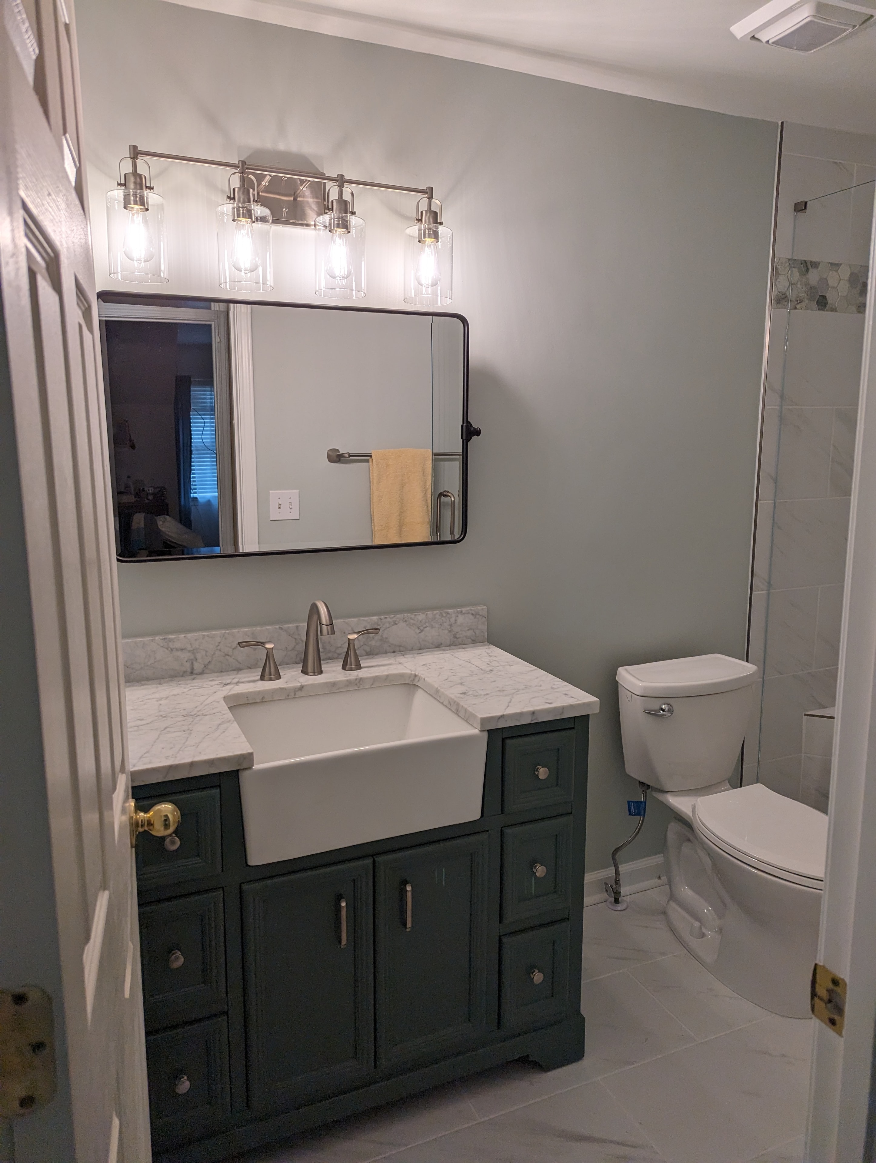 Bathroom after renovation – dark green farmhouse vanity with marble countertop
